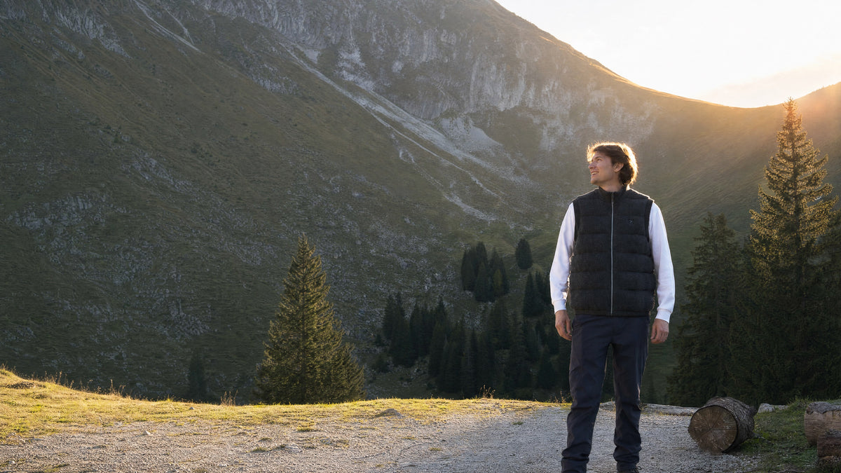 Homme en gilet chauffant Maison Polar face aux montagnes au coucher du soleil